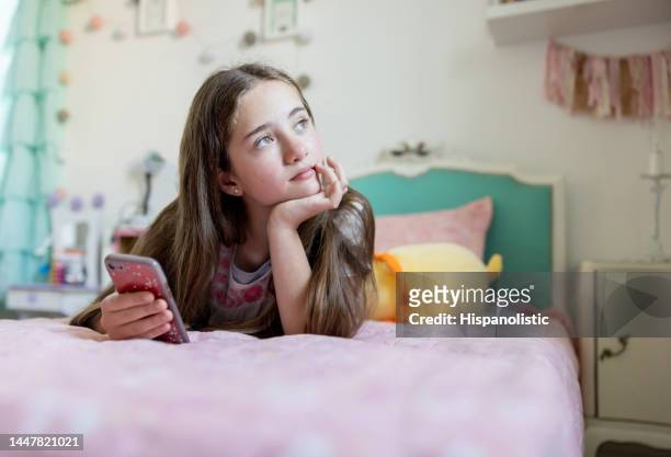 thoughtful teenage girl at home using her cell phone - beds dreaming children stock pictures, royalty-free photos & images