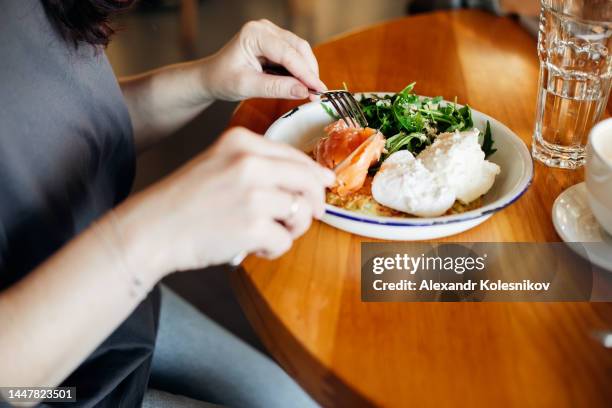 eating healthy breakfast. woman having lunch or breakfast. zucchini pancake, cheese, poached egg, salmon fish, arugula and cup of coffee. clean eating, dieting, detox, vegetarian food concept - kazakhstan food stock pictures, royalty-free photos & images