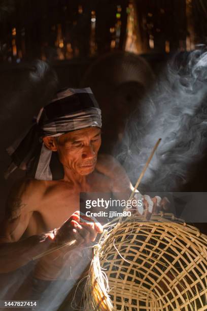 asian village lifestyle, moment a local male adult uncle basket weaver maker making bamboo basket and hat in a dry grass built room, very beautiful scenic view - making a basket imagens e fotografias de stock