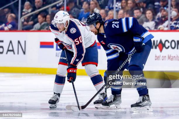 Eric Robinson of the Columbus Blue Jackets and Blake Wheeler of the Winnipeg Jets get set during a third period face-off at the Canada Life Centre on...