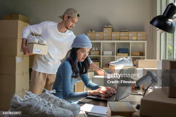 la donna asiatica e l'uomo venditore online preparano la scatola dei pacchi e controllano gli ordini di prodotto per la consegna al cliente. - commercio elettronico foto e immagini stock