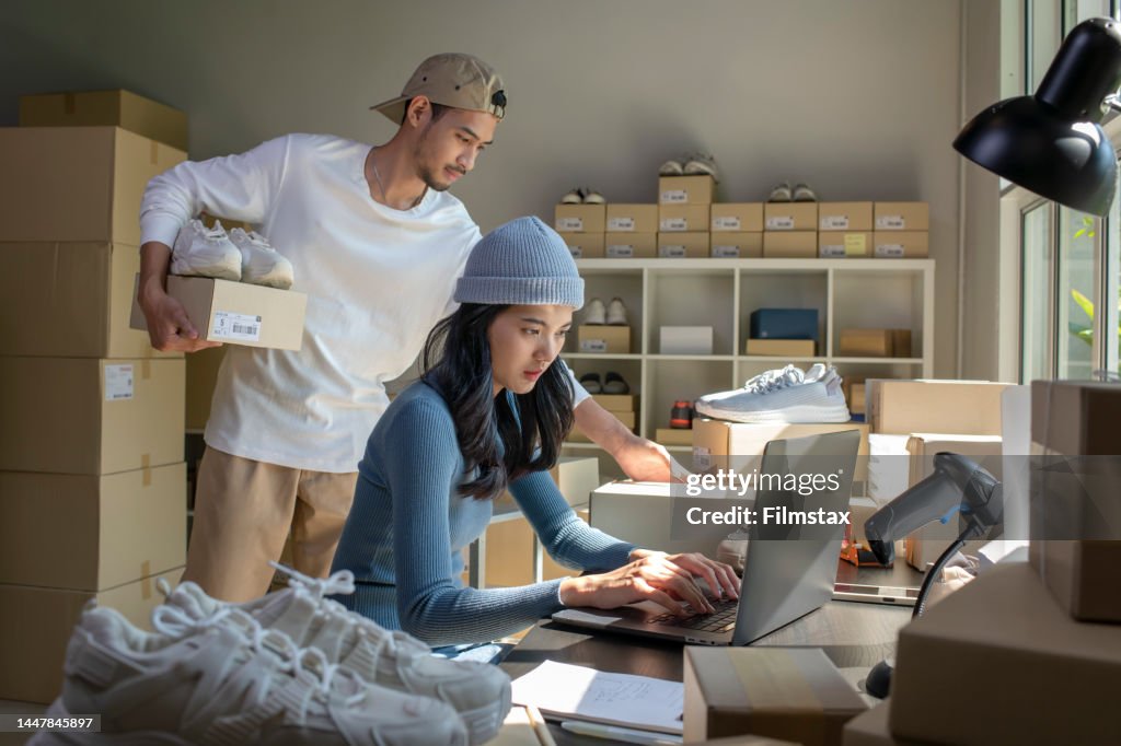 Asian woman and man online seller prepare parcel box and check orders of product for deliver to customer.