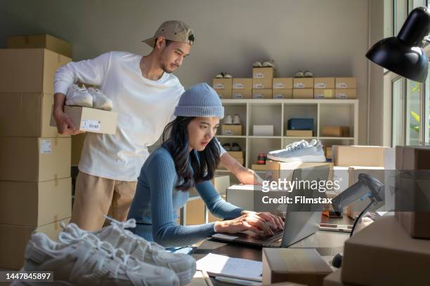 asian woman and man online seller prepare parcel box and check orders of product for deliver to customer. - market trader stockfoto's en -beelden