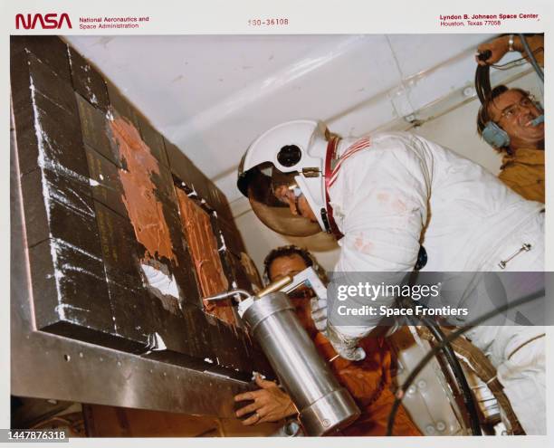 American NASA astronaut and physician Anna Lee Fisher using an applicator - part of the Thermal Protection System Repair Kit - to repair a damaged...