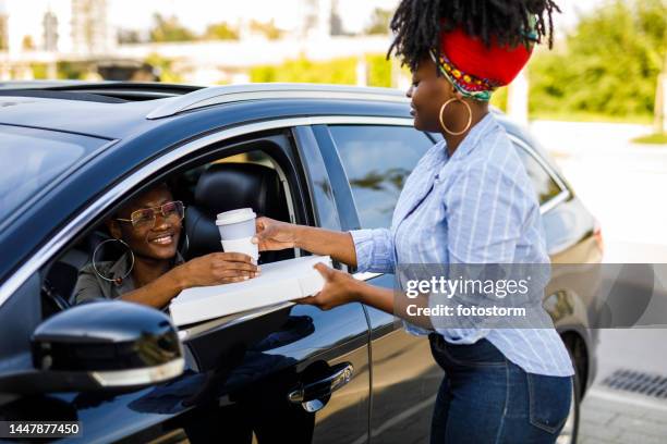service worker delivering a pizza and a takeaway coffee to a customer at the drive through - drive through stock pictures, royalty-free photos & images