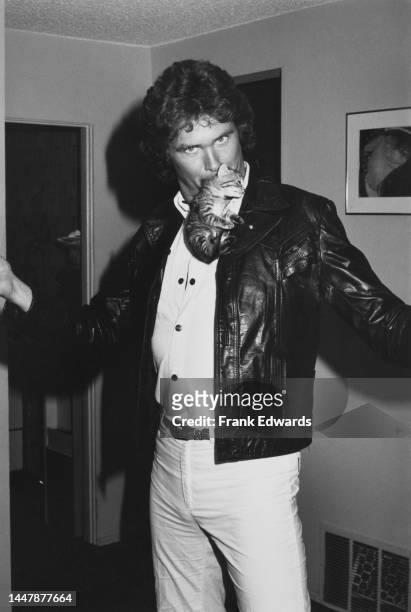 American actor and singer David Hasselhoff, wearing a black leather jacket, poses with a kitten in his mouth, at Hasselhoff's Hollywood Hills home in...