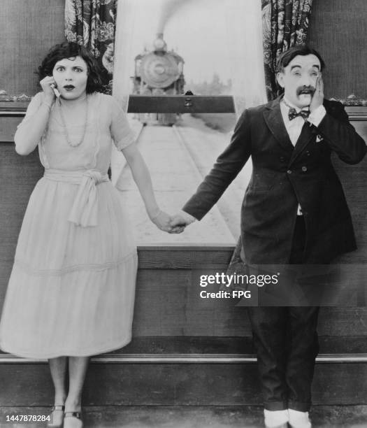 American actress Marie Mosquini and Australian actor and vaudevillian Snub Pollard holding hands, each holding their free hand to their face in...