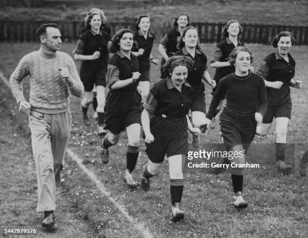 Football coach Freddie Over leads the players of Friary Brewery girls' football team during a training session, in Guildford, Surrey, 1st May 1940....