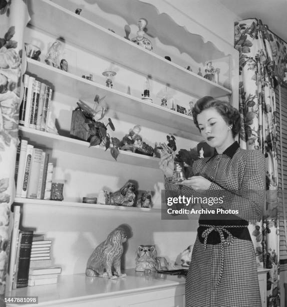 American actress, singer and dancer Shirley Temple with her collection of miniature lamps on shelves in her bedroom at the family home in Los...