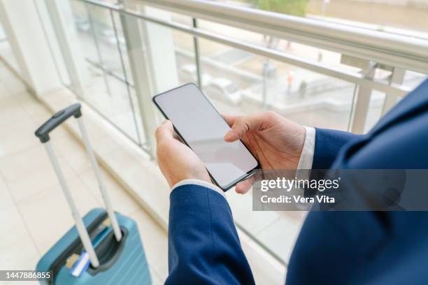 close up of unrecognizable businessman using smartphone blank screen mockup on white airport hall - airport mockup stock pictures, royalty-free photos & images