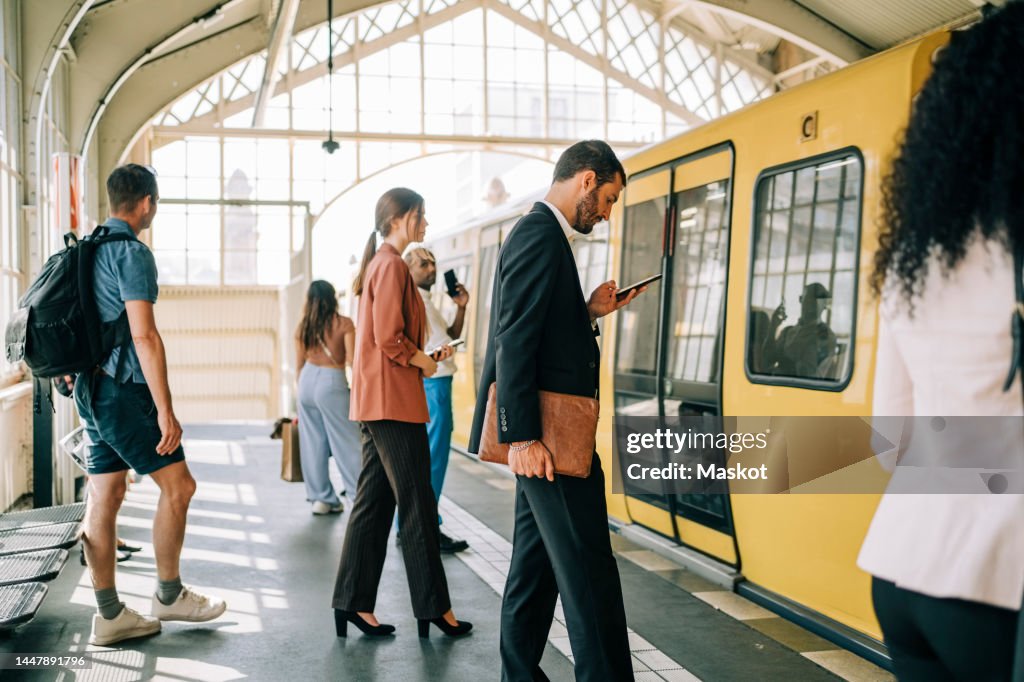 Businesswomen and businessman standing by train at railroad station