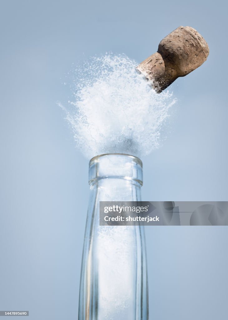Close-up of liquid and a cork exploding out of a long neck bottle