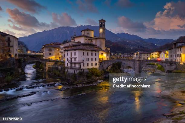 aerial villagescape with mountain backdrop at night, san giovanni bianco, val brembana, bergamo, lombardy, italy - bergamo stock pictures, royalty-free photos & images