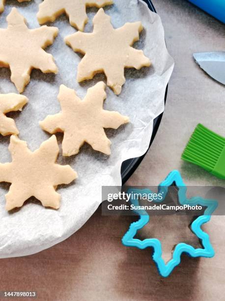 overhead view of raw snowflake shaped cookies on a baking tray - pastry cutter fotografías e imágenes de stock