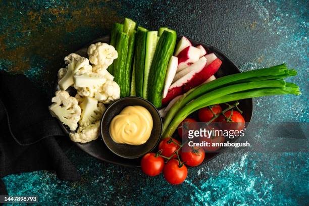 overhead view of a bowl of raw cauliflower, cucumber, radish, spring onion and cherry tomatoes with mayonnaise dip - crudites stock pictures, royalty-free photos & images