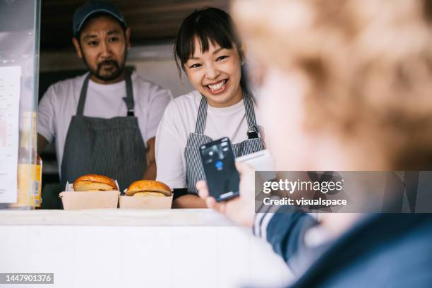 cliente che effettua un pagamento mobile al camion di cibo - furgone ambulante foto e immagini stock