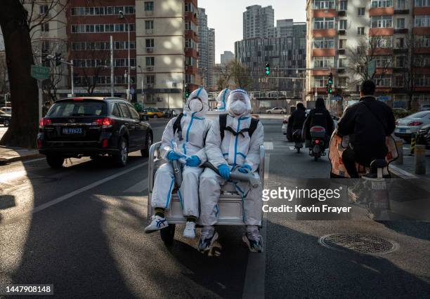 Epidemic control workers wear PPE as they ride on the back of a three wheeler on their way to disinfect an epidemic area on December 9, 2022 in...