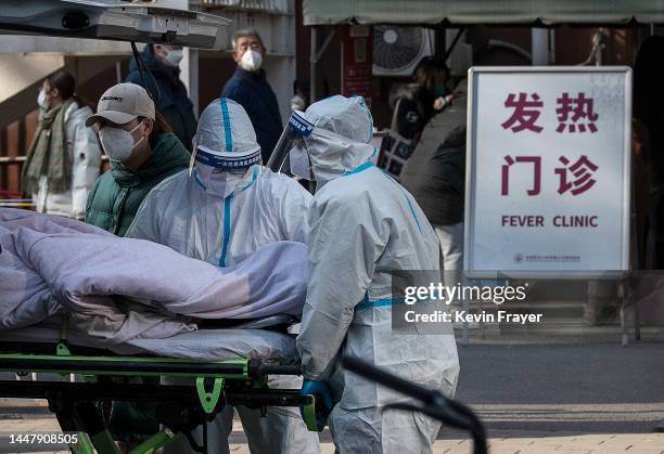 Medical workers wear PPE as they push a patient on a stretcher outside a fever clinic on December 9, 2022 in Beijing, China. As part of a 10 point...