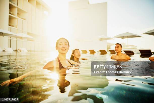 Medium shot of smiling woman relaxing in pool with family at resort