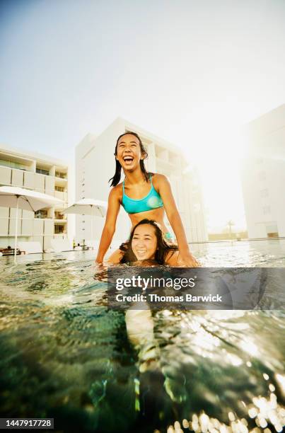 wide shot girl riding on sisters shoulders while playing in pool - brightly lit stock pictures, royalty-free photos & images