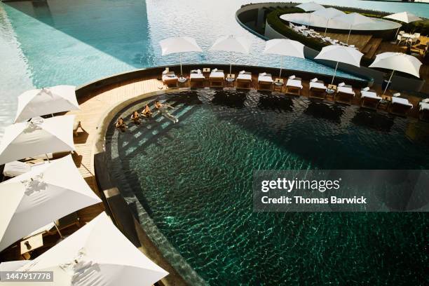 wide shot aerial view of family relaxing in pool at tropical resort - stéréotype de la classe supérieure photos et images de collection