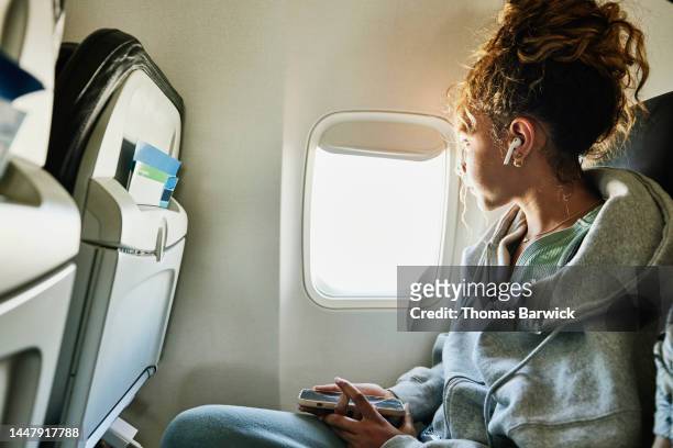 medium shot of girl looking out window of commercial airplane - travel stock-fotos und bilder