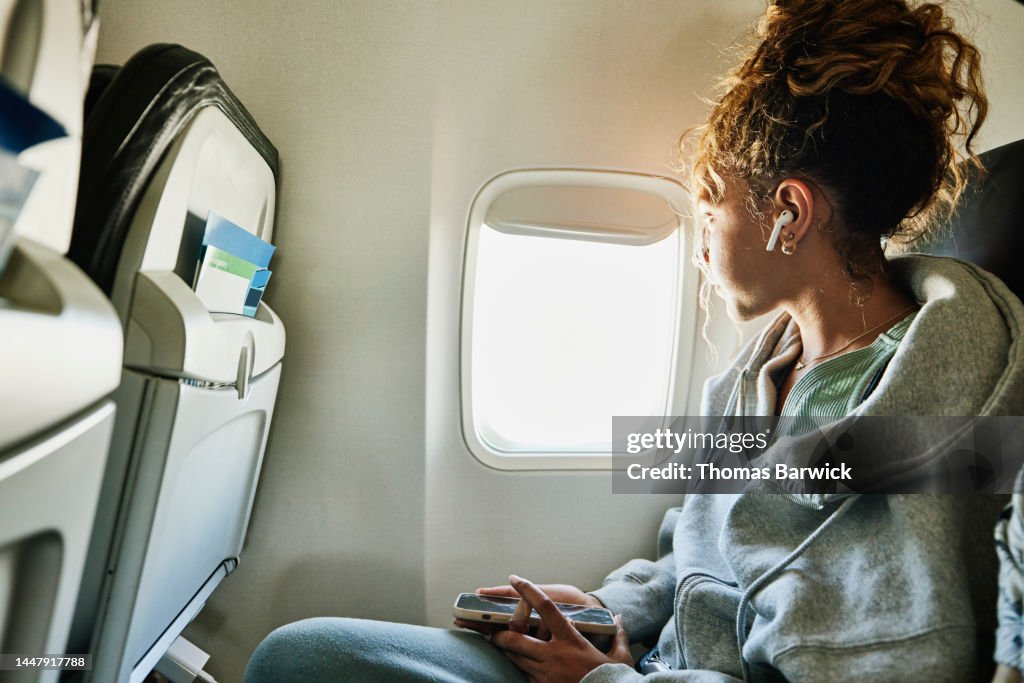 Medium shot of girl looking out window of commercial airplane