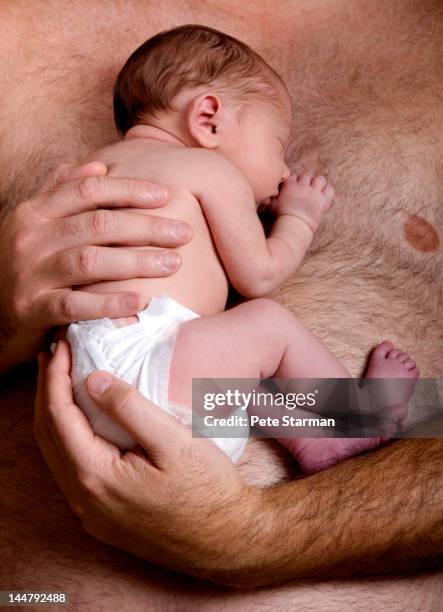 shirtless father holding a new born baby - female hairy chest stock-fotos und bilder