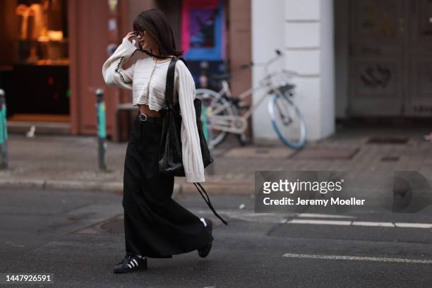 Jihoon Kim seen wearing Axel Arigato white cardigan, black long skirt from source unknown, Miu Miu black handbag and black Adidas Superstar sneaker...