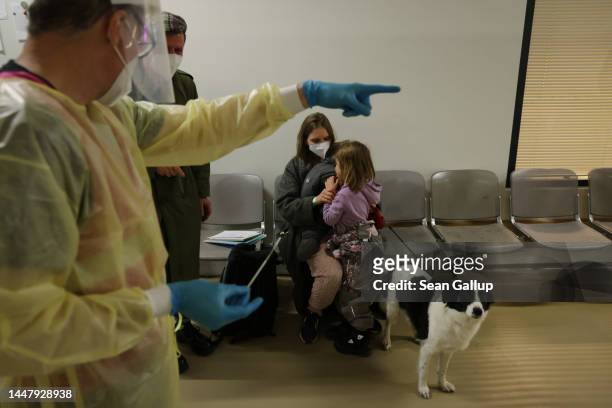 Health worker directs Ukrainian refugee Mitya Gerasimov, a musician from Kyiv, after giving him a Covid test as Mitya's wife Yulia sits with their...