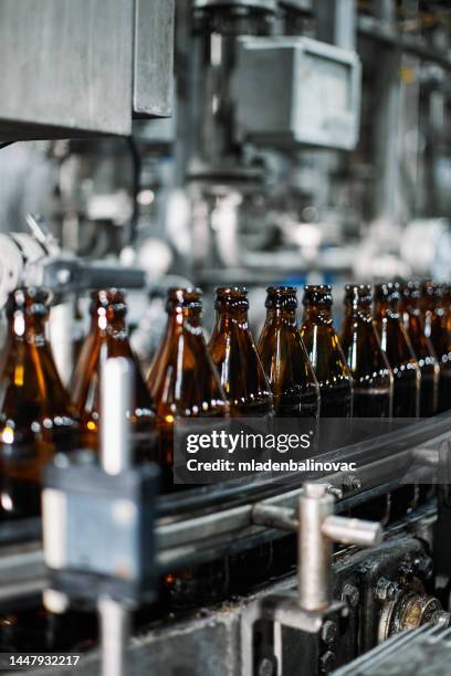 close-up on a bottling machine operating at a beer factory - bottle production line stock pictures, royalty-free photos & images