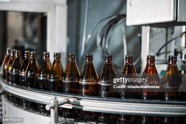 nahaufnahme einer abfüllmaschine in einer bierfabrik - bierflaschen fließband stock-fotos und bilder