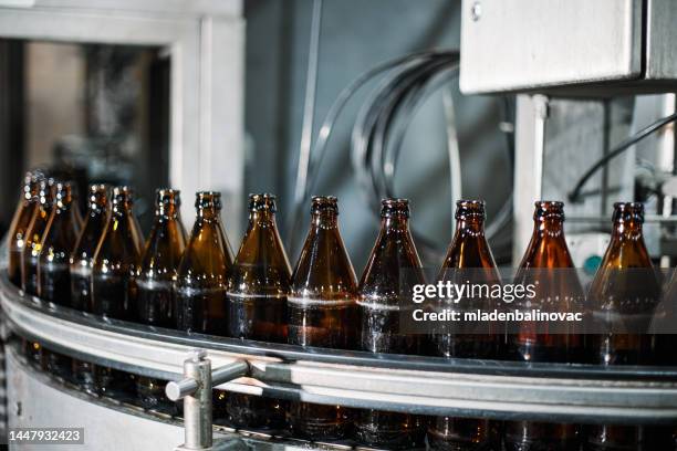 close-up on a bottling machine operating at a beer factory - bottling plant stock pictures, royalty-free photos & images
