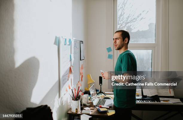 a man concentrates in a home-office environment, looking intently at nothing in-particular as he thinks - staring stock pictures, royalty-free photos & images
