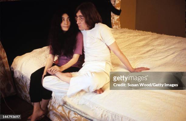 Japanese-born artist and musician Yoko Ono and British musican and artist John Lennon sit together on a bed, December 1968.