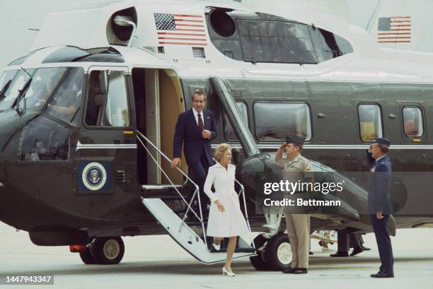 American politician Richard Nixon and his wife, former First Lady Pat Nixon leaving Marine One, a Sikorsky SH-3H Sea King, saluted by military...