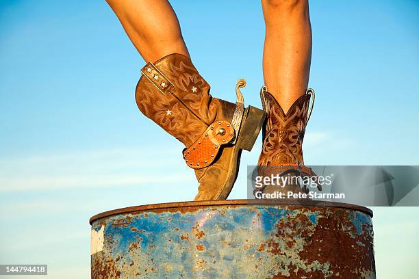 cowgirl on an oil drum displaying her spurs - boot spur stock pictures, royalty-free photos & images