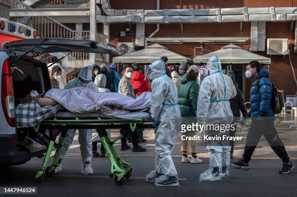 Medical workers wear PPE as they arrive with a patient on a stretcher at a fever clinic on December 9, 2022 in Beijing, China. In a major shift in...