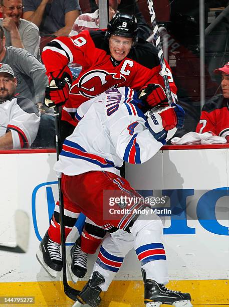 Zach Parise of the New Jersey Devils is checked hard into the boards by Michael Del Zotto of the New York Rangers in Game Three of the Eastern...