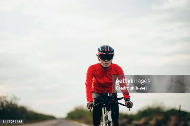 female triathlete cycling on country road - womens triathlon stock pictures, royalty-free photos & images