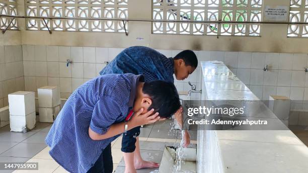 kind muslim nimmt waschung zum gebet - rituelle-waschung-im-islam stock-fotos und bilder