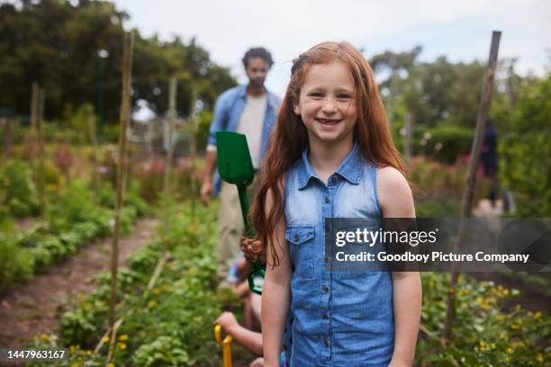 smiling young girl standing in a community garden during a class field trip - portrait of school children and female teacher in field stock pictures, royalty-free photos & images