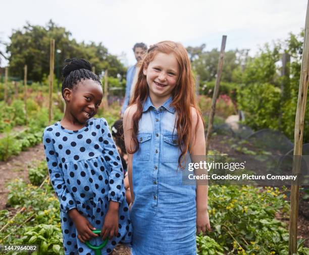 smiling girls standing in a during a field trip to a community garden - portrait of school children and female teacher in field stock pictures, royalty-free photos & images