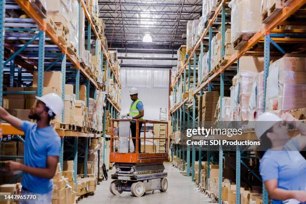 diverse employees perform quality control on merchandise in warehouse - scissor lift stock pictures, royalty-free photos & images