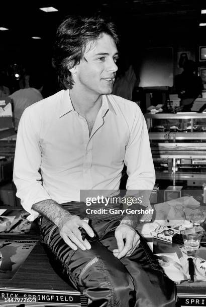 View of Australian-American Pop musician and actor Rick Springfield, seated on a desk, during an album signing at J&R Music store, New York, New...
