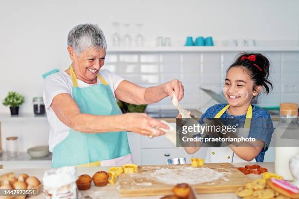 grandmother and granddaughter cooking together in a kitchen - funny grandma stock pictures, royalty-free photos & images