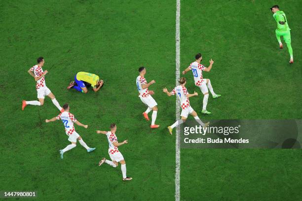 Croatia players celebrate their win via a penalty shootout as Marquinhos of Brazil reacts during the FIFA World Cup Qatar 2022 quarter final match...