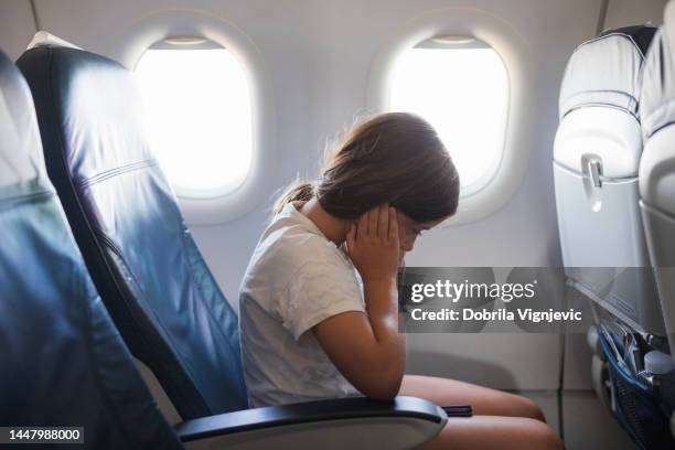 girl having an earache, sitting on a passenger's seat in a airplane - pressure airplane stock pictures, royalty-free photos & images