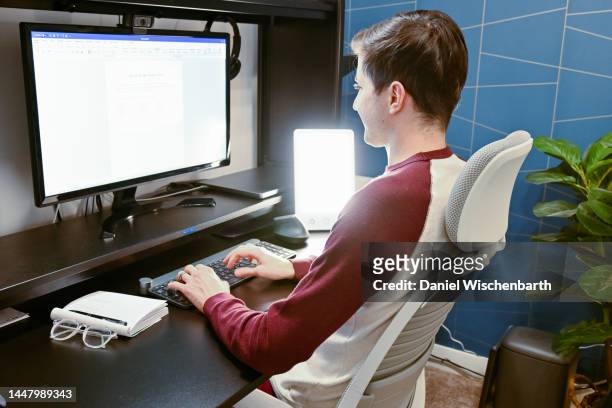 junger mann benutzt therapielampe im homeoffice - winterdepression stock-fotos und bilder