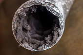 A dirty laundry flexible aluminum dryer vent duct ductwork filled with lint, dust and dirt